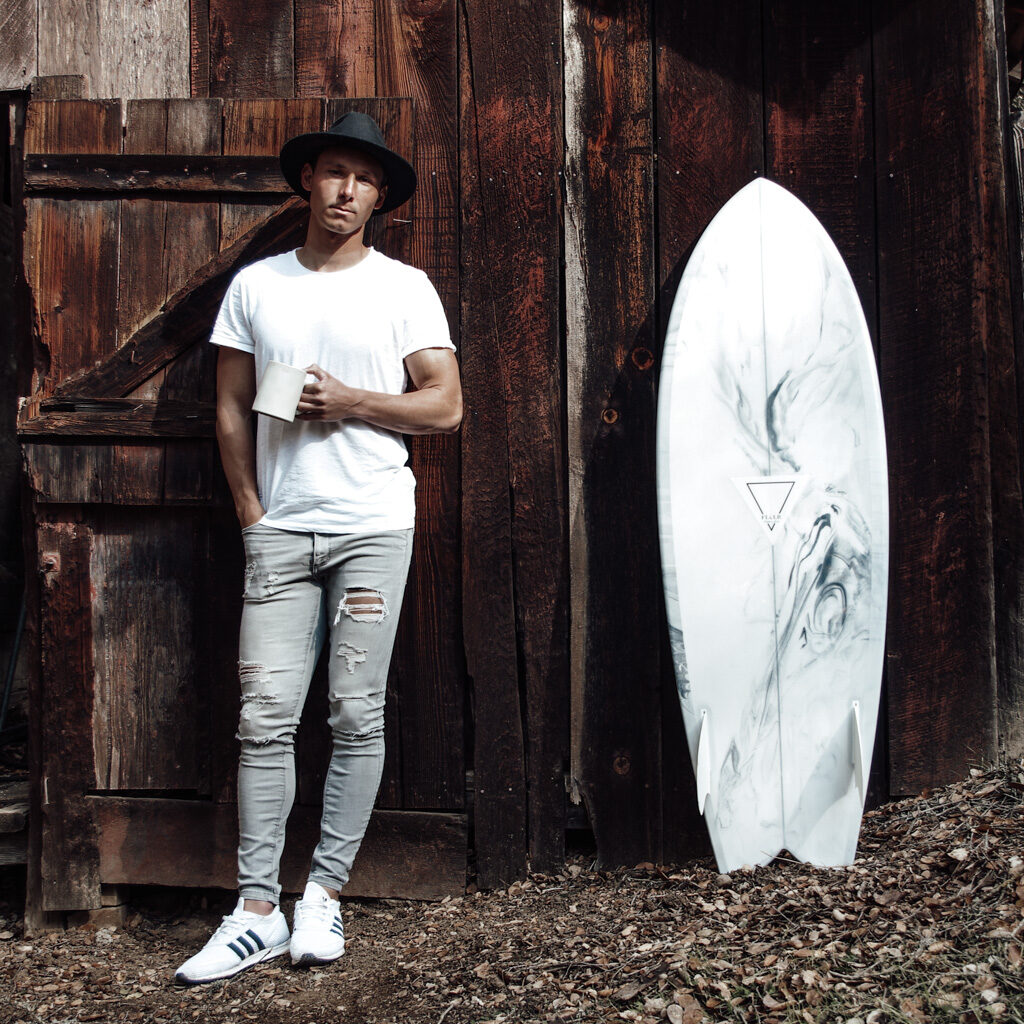 West-Coast based photographer Chris Koski stands with a cup of coffee and one of his favorite fish surfboards